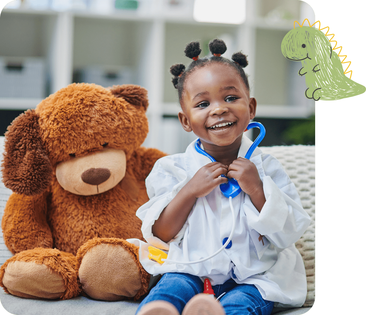 Smiling young girl in a doctor's coat with a stethoscope, playing pretend doctor next to a teddy bear